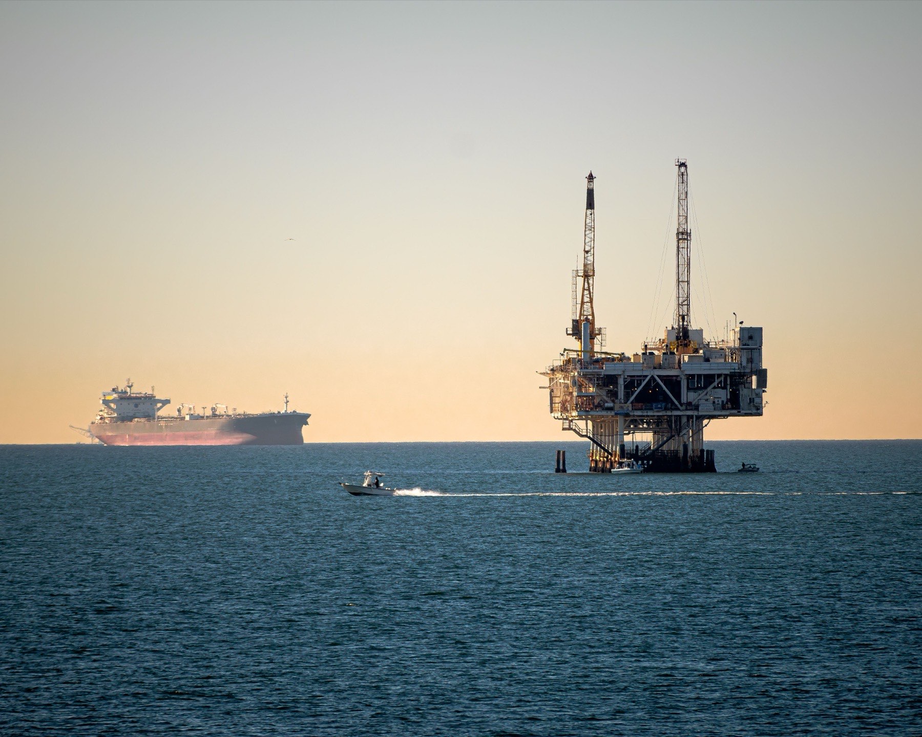 Offshore oil platform with a tanker on the horizon at sunset