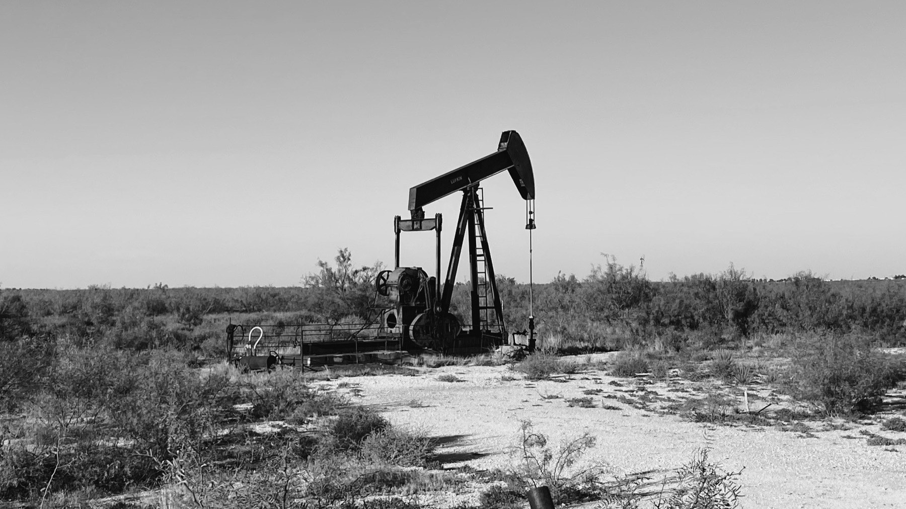 Black and white photo of a pumpjack in a West Texas oilfield