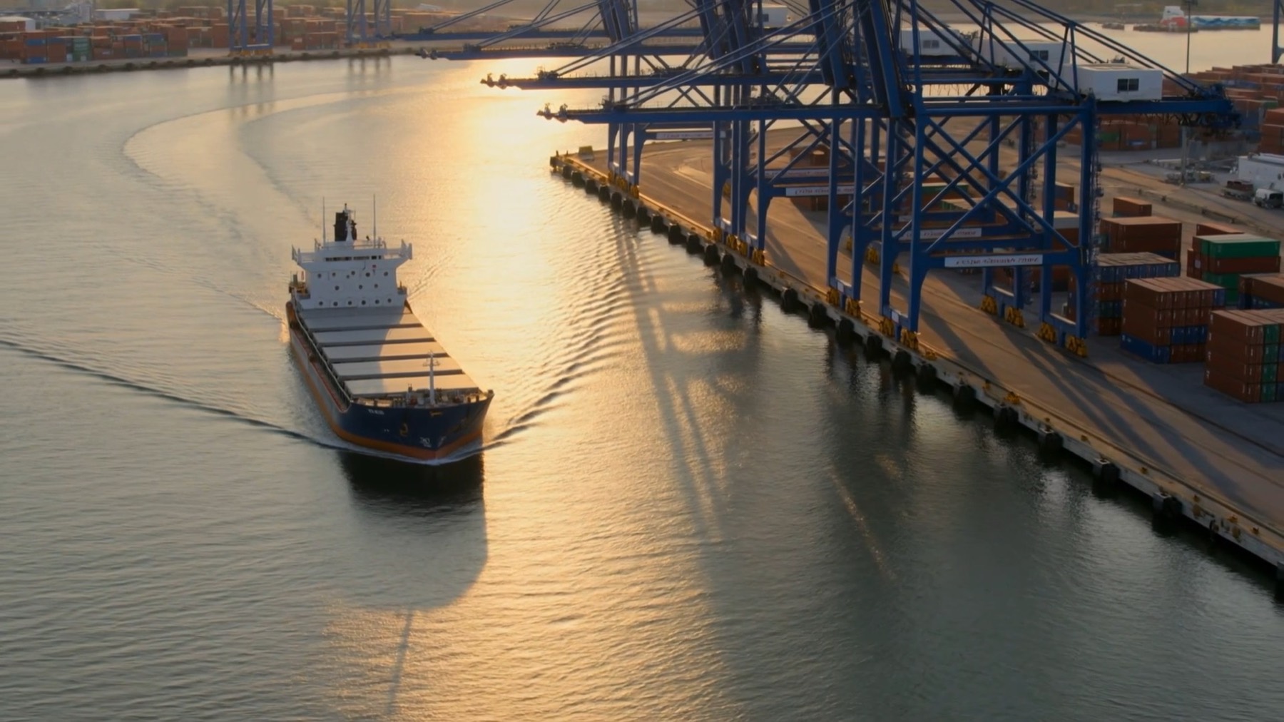 Cargo ship arriving at a container port at golden hour